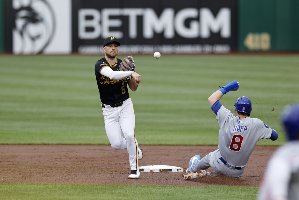 Pirates second baseman Brandon Lowe, wearing a black jersey, steps onto the grass in front of second base and throws to first base while avoiding a sliding runner.