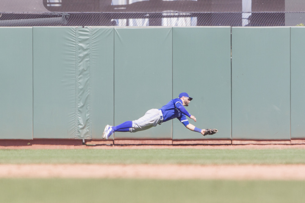 Kevin Pillar, wearing blue jersey and grey pants, dives fully to the right in making a catch in Oracle Park.